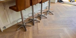 Karndean Herringbone flooring in neutral coloured kitchen installed with brown breakfast bar chairs