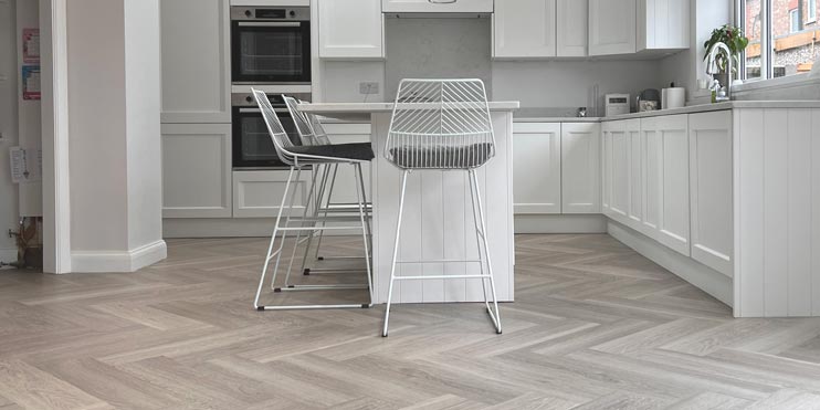 light grey/white Oak Herringbone flooring installed in a white kitchen
