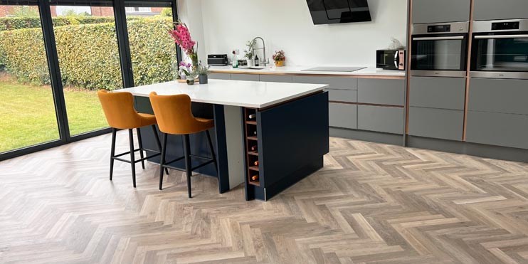 Oak Herringbone flooring installed in a grey and navy blue kitchen