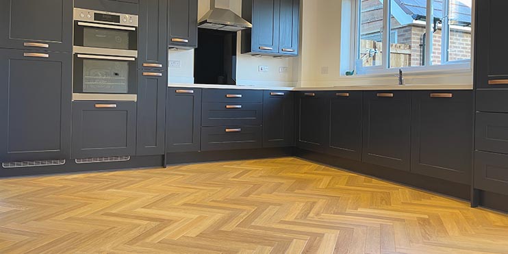 Oak Herringbone flooring installed in a navy blue kitchen