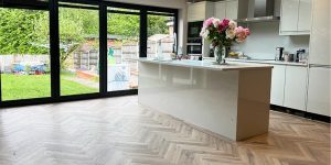 Neutral oak coloured LVT flooring installed in a herringbone pattern to a large luxury kitchen and diner in Sale, Cheshire