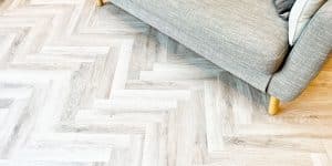 Off white and grey oak coloured LVT flooring installed in a herringbone pattern to a living room in Urmston