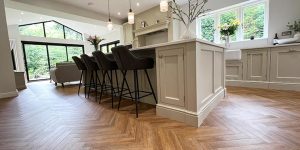 Smoked oak coloured LVT flooring installed in a herringbone pattern to a large luxury kitchen