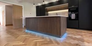 Real herringbone flooring in natural oak installed in a modern black kitchen